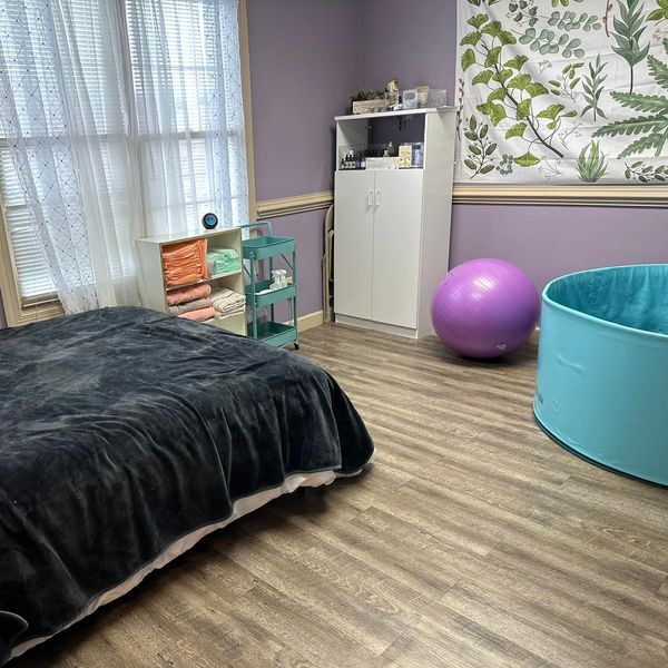 Cozy therapy room with a bed, exercise ball, and storage cabinets.