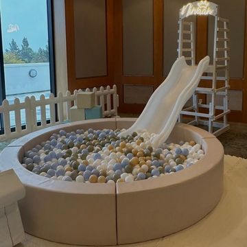 Indoor ball pit with a white slide and pastel-colored balls in a soft play area.