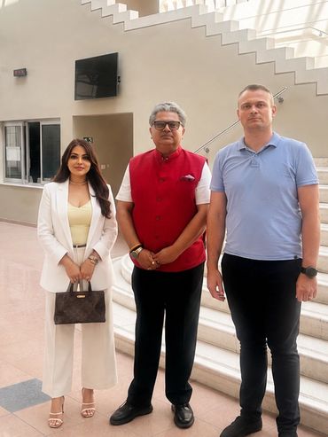 Three people standing indoors near a staircase.