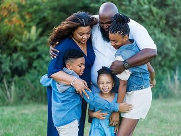 A joyful family of five embracing outdoors in a green park.