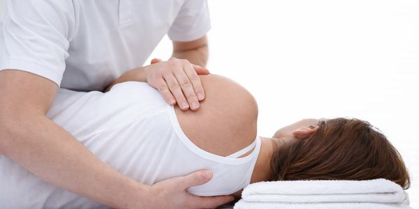 Pregnant woman receiving a gentle chiropractic adjustment.