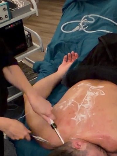 Person receiving a back treatment with a scraping tool.