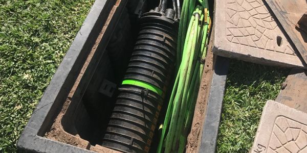 Open underground utility box with cables inside.