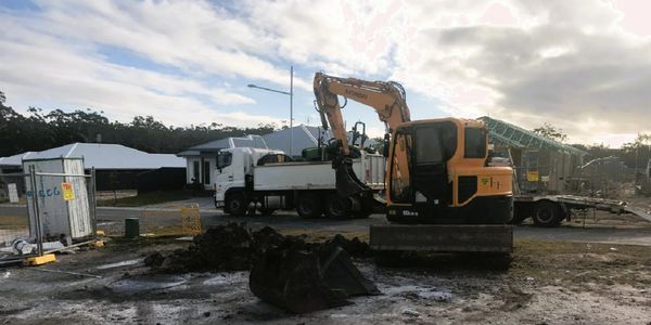 Excavator and truck at a construction site during cloudy weather.