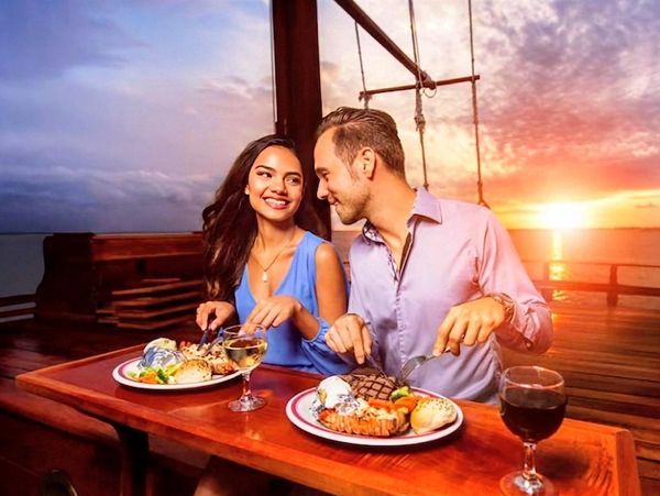 Couple enjoying a romantic dinner on a boat at sunset.