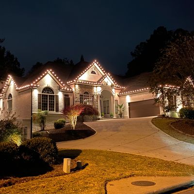 A beautifully lit house at night with decorative lights along the roofline.