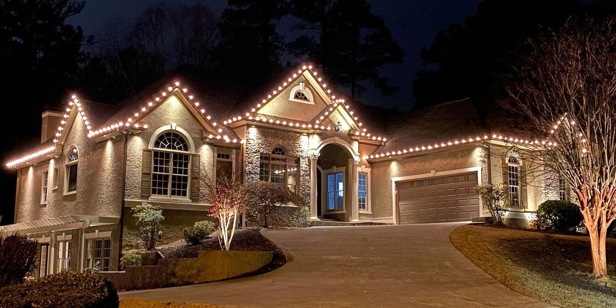 A beautifully lit house at night with decorative lights along the roofline.