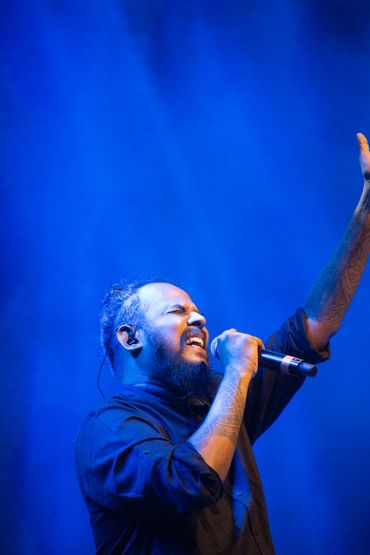 Male singer passionately performing on stage with blue lighting.