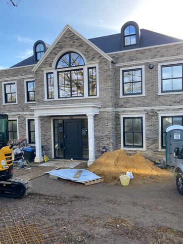 Large brick house under construction with construction materials outside.