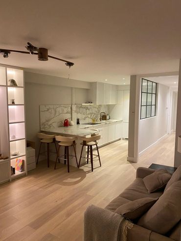 Modern kitchen with marble countertops, bar stools, and cozy living area.