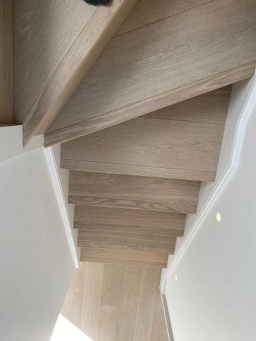 Top-down view of modern wooden stairs with light walls and subtle lighting.