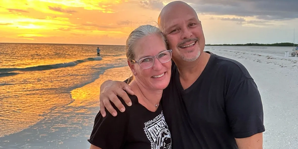 Couple smiling on the beach at sunset.