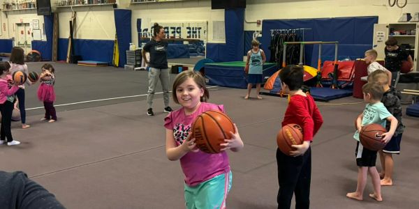 Kids practicing basketball in a gym.