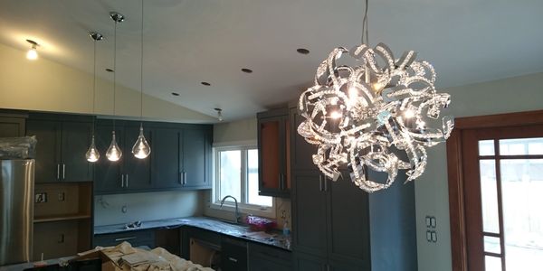 Modern kitchen with unique spiral chandelier and pendant lights.