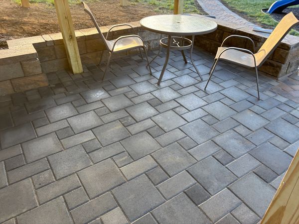 Outdoor patio with two chairs and a round glass table on stone tiles.