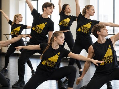 A group of young dancers practicing in a studio wearing matching black outfits.