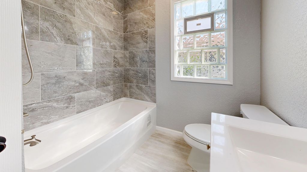 Moderne badkamer met grijze tegels en wit sanitair.