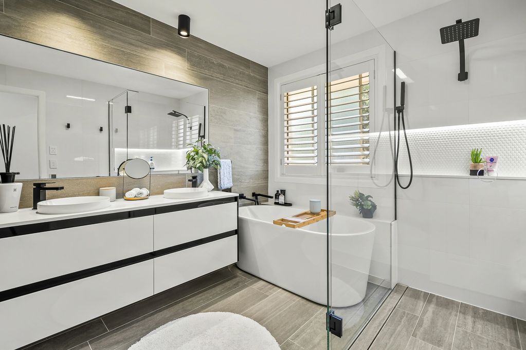 Moderne badkamer met dubbele wastafels en vrijstaand bad.