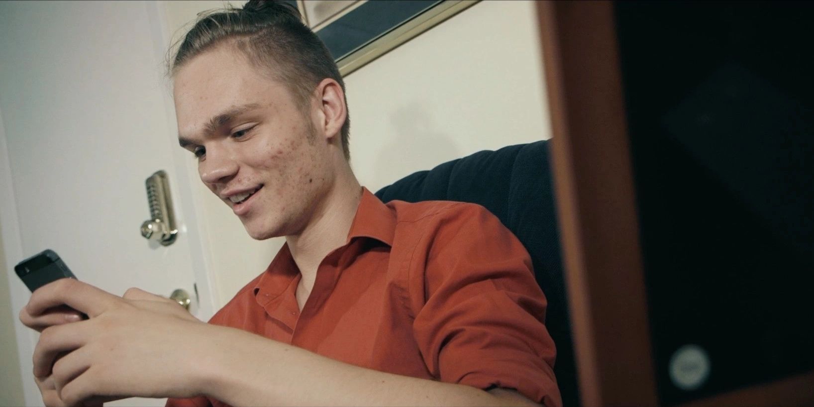 An image of a man on a rocking chair texting on his iPhone.