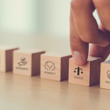 Hand arranging wooden blocks labeled with core values like ethics and respect.
