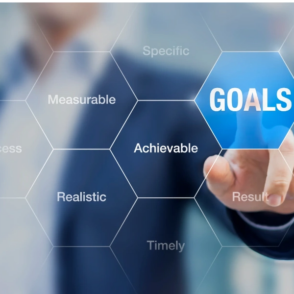 Businessman pointing at hexagonal icon labeled 'GOALS' with related terms.