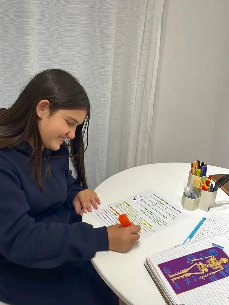 Girl highlighting her study notes at a white round table.