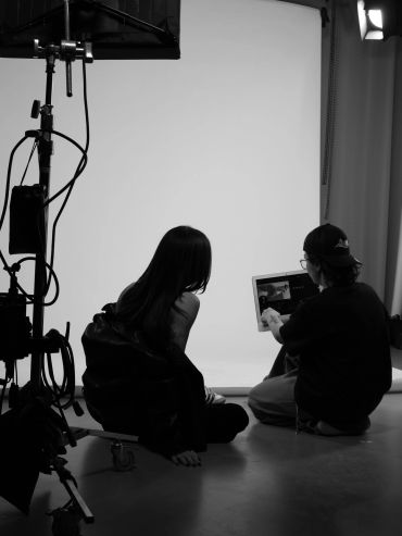 Two people reviewing images on a tablet in a photography studio.