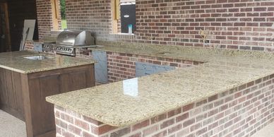 An outdoor kitchen with tan/beige granite countertops