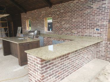 An outdoor kitchen with tan and beige granite countertops
