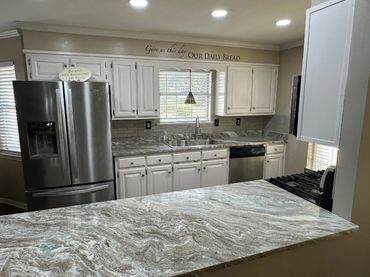 A kitchen with white cabinets and countertops with brown, gray, and white veining.