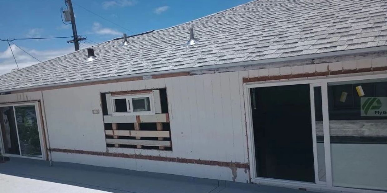 House exterior with new roof and boarded window under renovation.