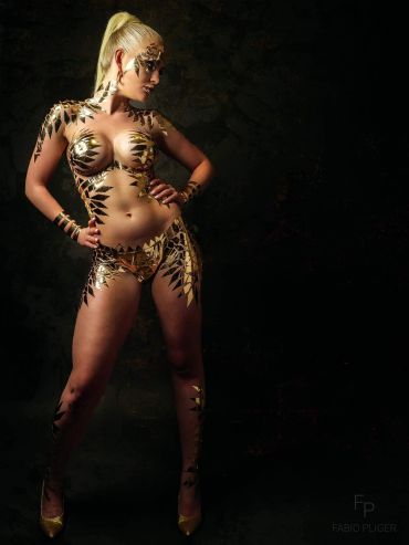 Woman covered in gold metallic body paint posing.