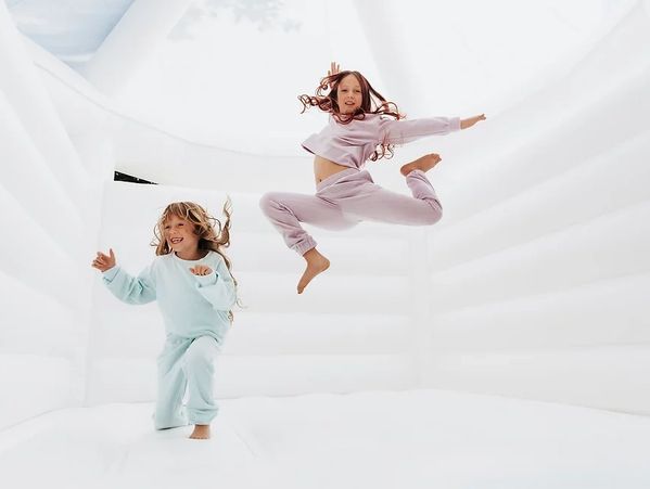 Toddlers jumping in a white bounce castle