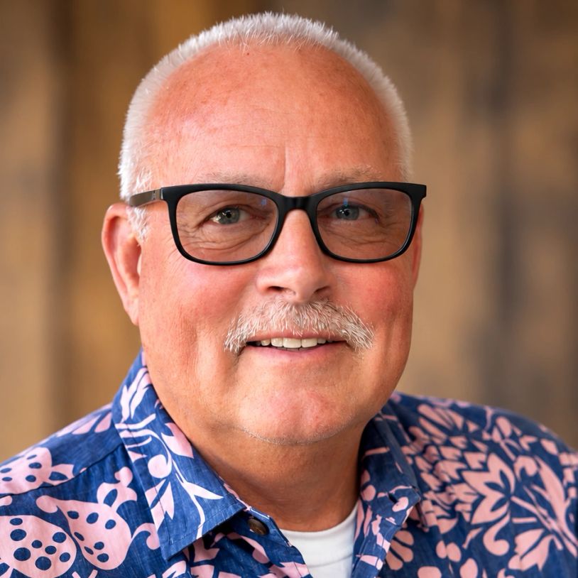 Smiling older man with glasses wearing a floral shirt.