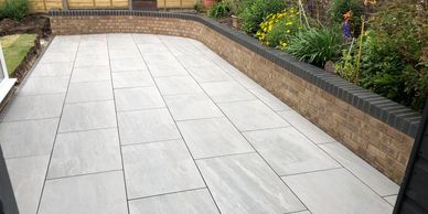 Kandla grey porcelain paving with raised brick planters 