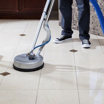 Person cleaning tiled floor with a professional floor scrubber.