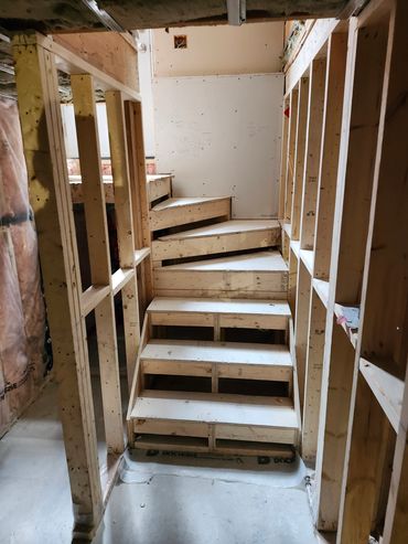 Wooden staircase under construction in framed walls.