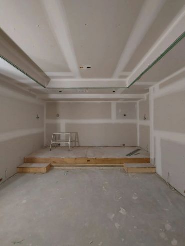 Room under construction with a raised platform and drywall.