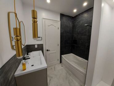 Modern bathroom with gold fixtures and dark tiled shower.