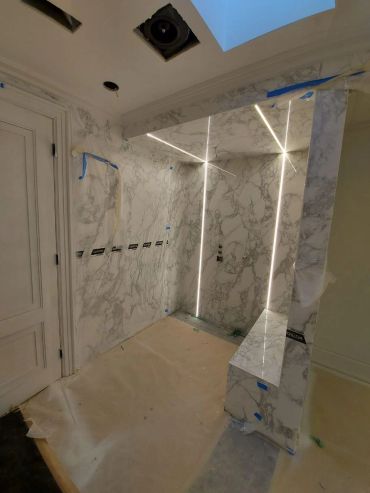Marble-clad shower area under construction with LED lighting.