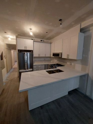 Modern kitchen with white cabinets and a marble countertop.