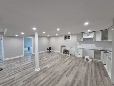 Spacious unfinished basement with light wood flooring and recessed lighting.