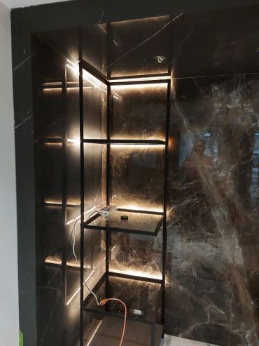 Modern shelving unit with mood lighting against marble wall.