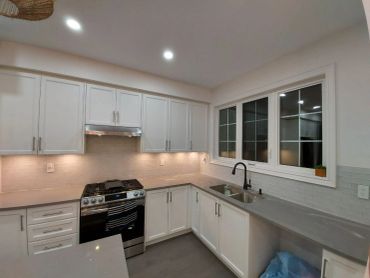 Modern kitchen with white cabinets and gray countertops.