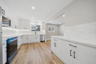 Modern kitchen with white cabinets and wooden floor.