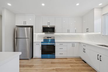 Modern kitchen with white cabinets and stainless steel appliances.