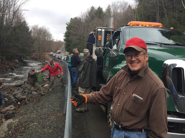 People working together near a river with trucks and equipment.