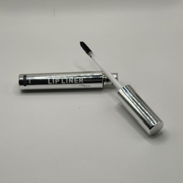 Silver lip liner with applicator brush on white surface.