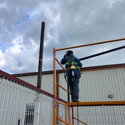 Trabajador en altura con arnés en andamio.