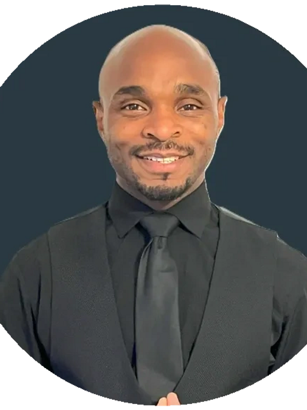 Smiling man dressed in formal black attire with tie and vest.
